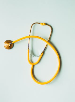 Top view of yellow medical stethoscope placed on white surface during coronavirus pandemic